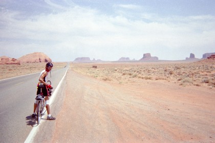 Adam straddling bike in the desert and looking back at camera