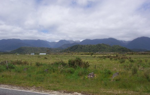 Roadside scene with field and mountains in the distance