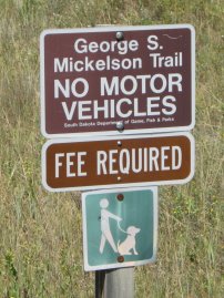 Signs, 'George S. Mickelson Trail, NO MOTOR VEHICLES, FEE REQUIRED, dogs on leash'