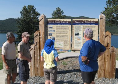 People looking at Pactola reservoir informational signboard