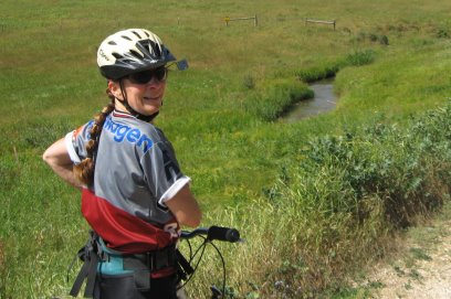 Sue looking back over her shoulder with field & stream in background