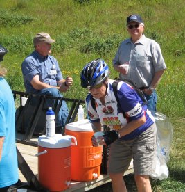Back end of trailer with two water jugs, two drivers chatting