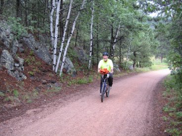Dale riding down trail toward camera with aspen trees in background
