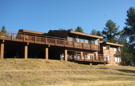 Large building with two levels of fenced deck, viewed from downhill