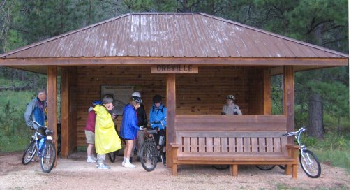 Riders huddling from the rain in shelter labeled 'Oreville'
