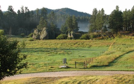 Green fields with fences and rock formations on the other side