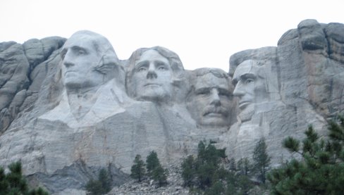 Sue standing besides Mt. Rushmore visitor center sign with the mountain in the background