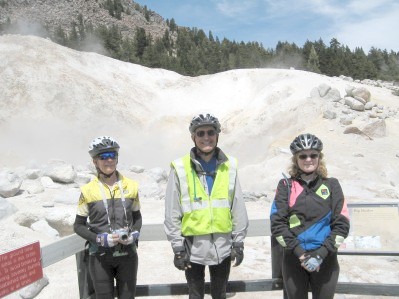 Three cyclists standing with steam rising behind them