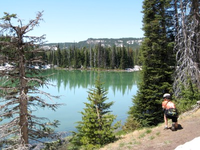 Sue taking a photo of a lake surrounded by trees