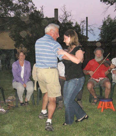 Liz and Alfred dancing while Dave plays fiddle in the background with Liz's proud mom Mary looking on